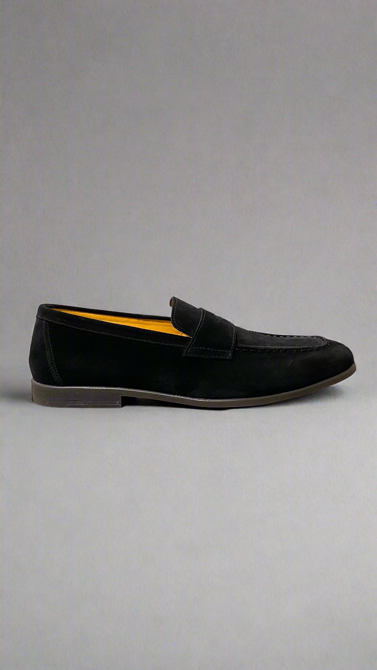 Black loafer shoe on a white platform with a neutral background