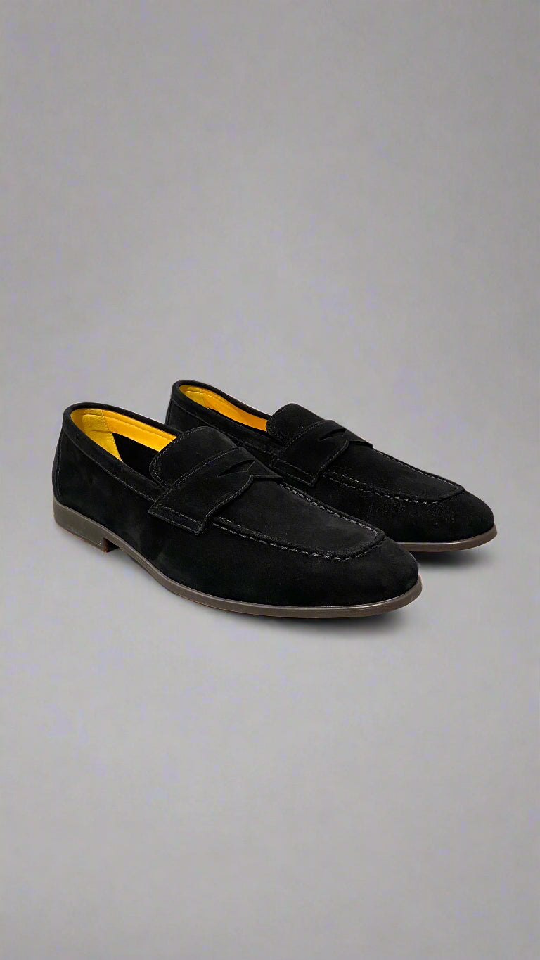 Black loafers with yellow interior on a white surface