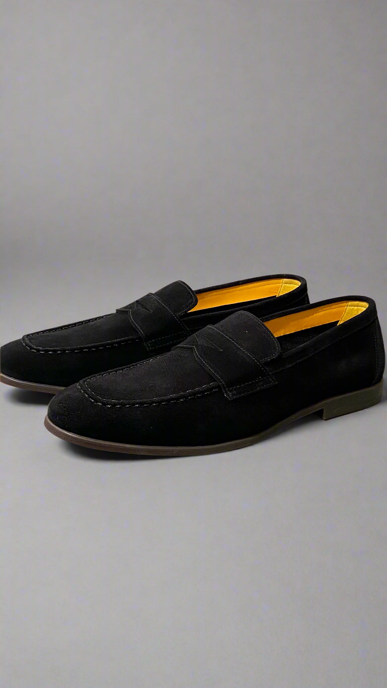Black loafers with yellow lining on a light gray surface