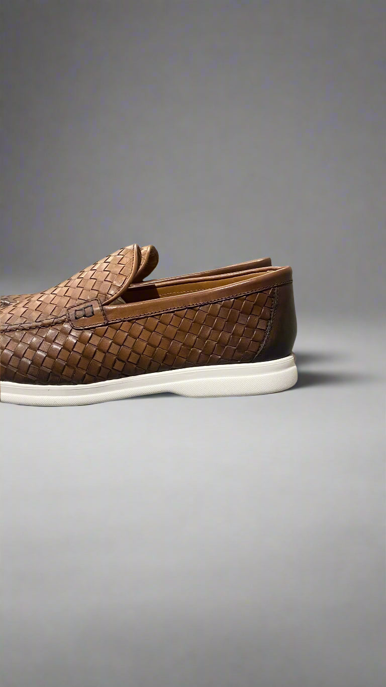 Brown woven loafer with white sole on a gray surface