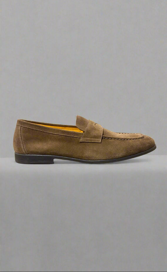 Brown loafer shoe on a gray surface with a neutral background