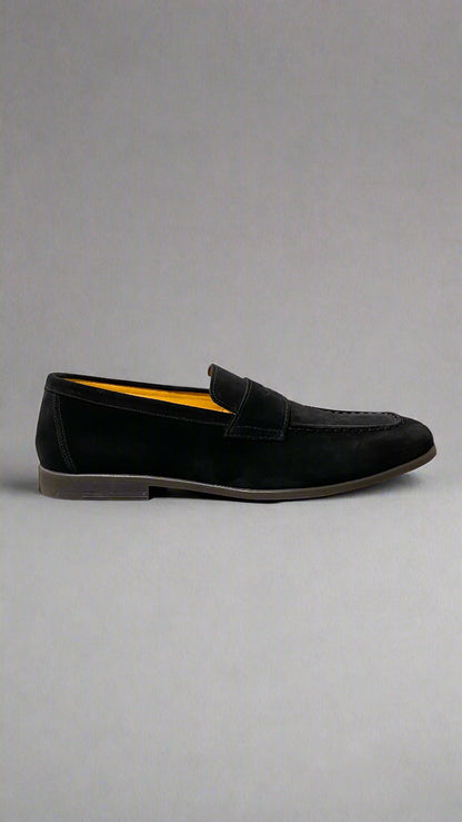 Black loafer shoe on a white platform with a neutral background