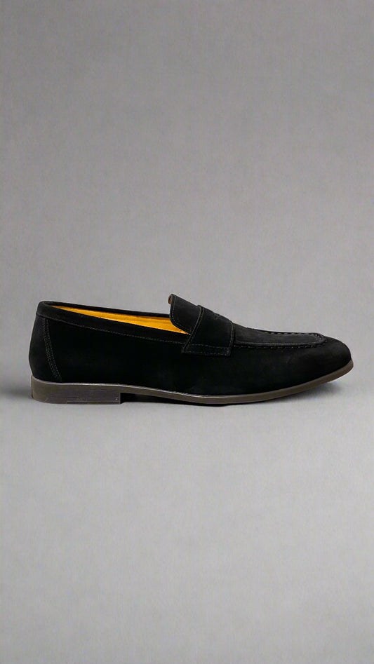 Black loafer shoe on a white platform with a neutral background