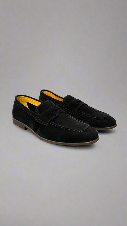 Black loafers with yellow interior on a white surface