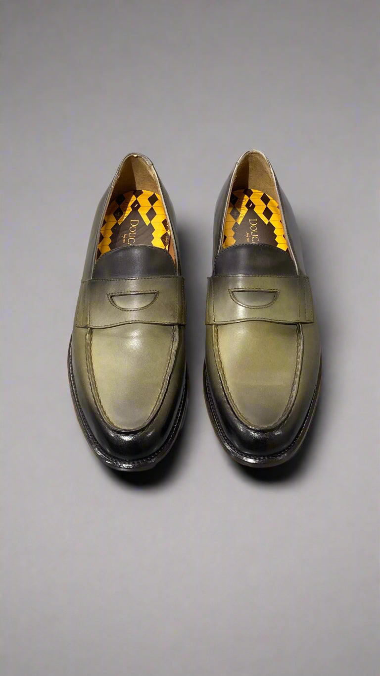 Pair of brown leather loafers with black soles on a white surface