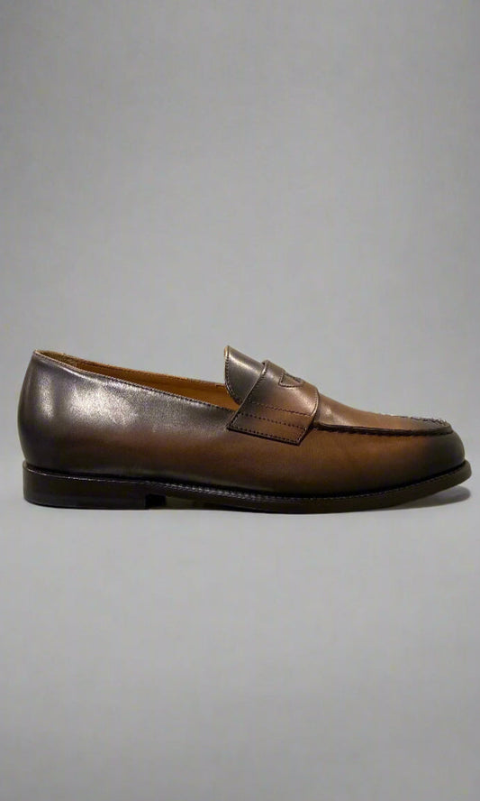 Brown leather loafer on a light gray surface with a neutral background