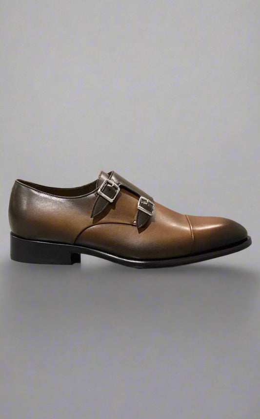 Brown leather shoe with a buckle on a light gray background
