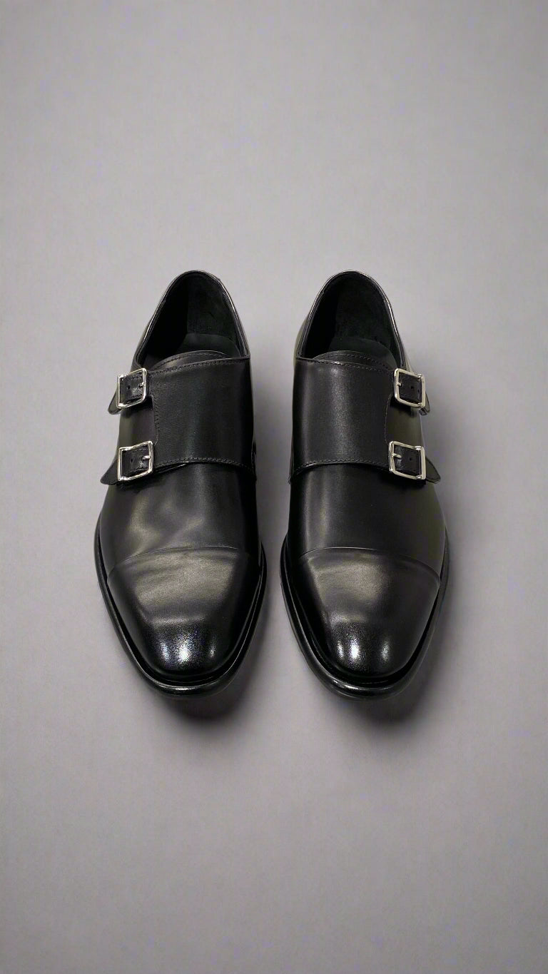 Pair of black monk strap shoes on a light gray surface