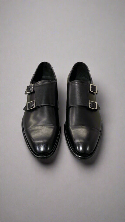 Pair of black monk strap shoes on a light gray surface