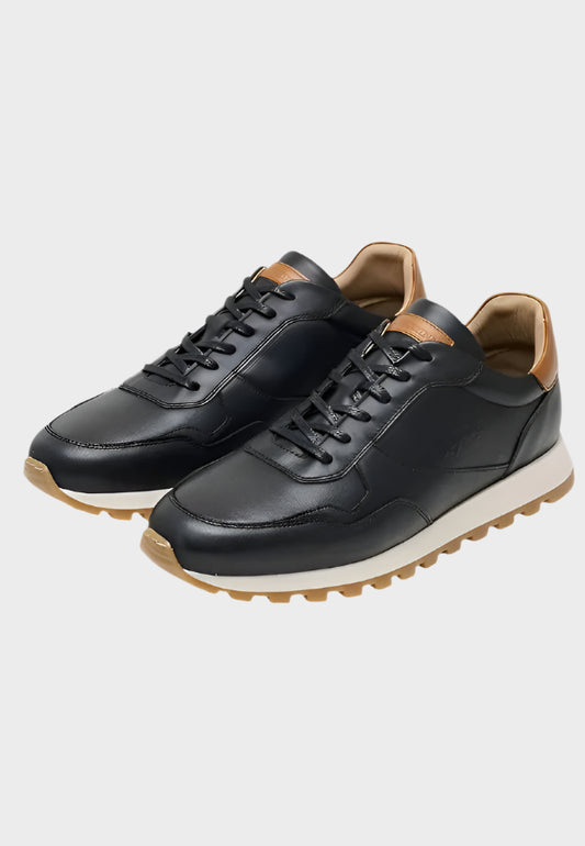 Pair of black leather sneakers with tan soles on a white background